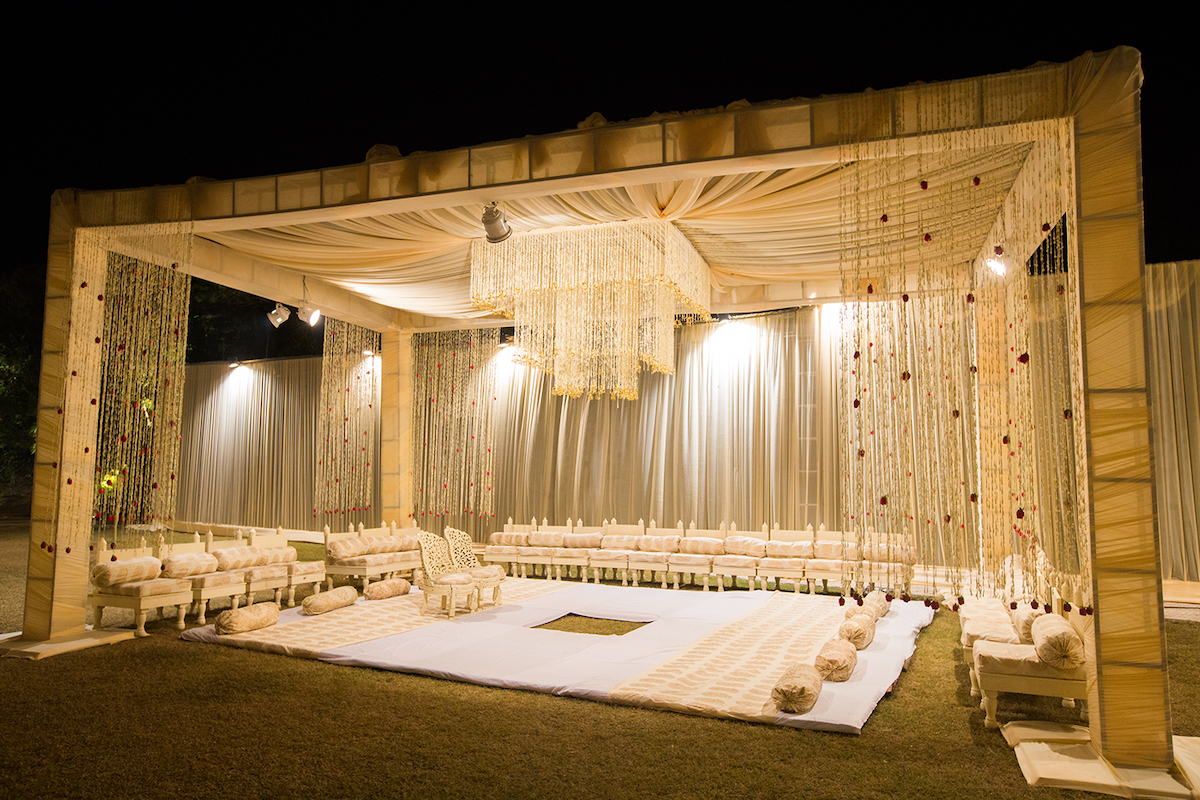 white mandap with cream and gold mandap chairs & decorated with tuberose flowers