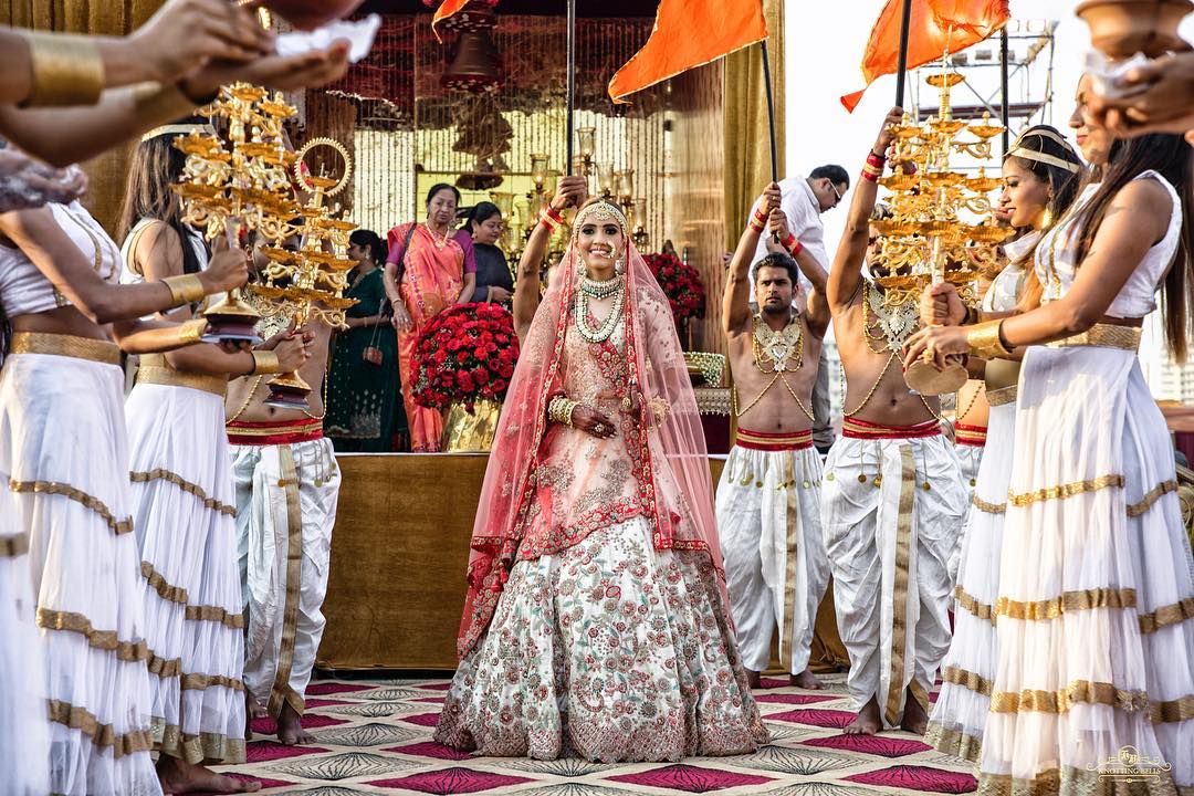 Bride entry in wedding with girls holding aarti lamps on both sides